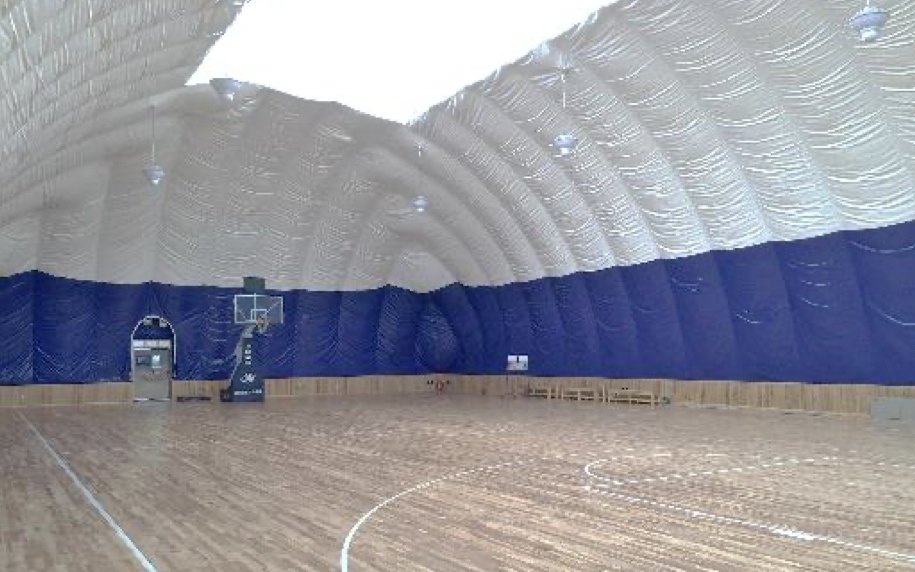 Basketball court under an air-supported dome, timber floor and blue perimeter wall